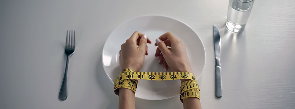 Hands tied with tapeline on empty plate, girl obsessed with counting calories