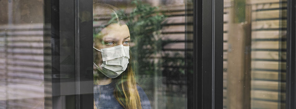 Teenage girl looking through window with mask